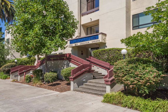 Front view of a multi-story building with stairs leading to an entrance.