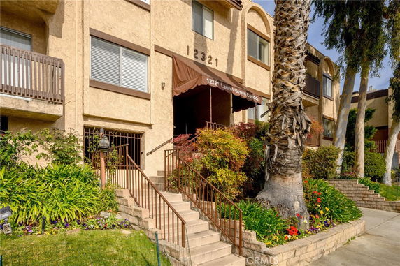 Front view of a multi-story residential building with an entrance staircase and canopy.