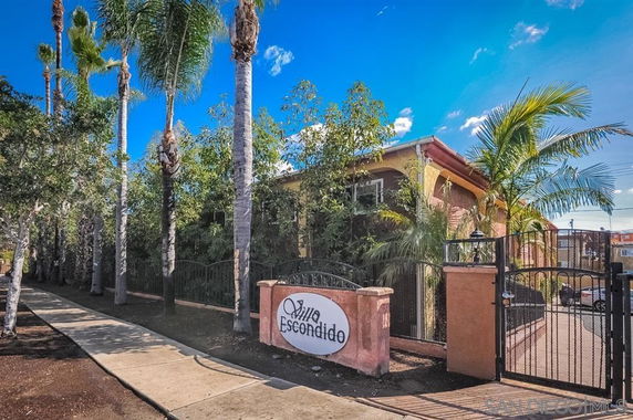 Front view of a building with a gated entrance and palm trees.
