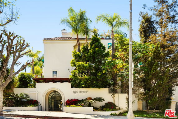 Front view of a multi-story building with arched entrance and surrounding trees.
