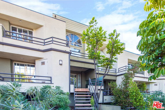 Front view of a multi-story building with balconies and stairs.