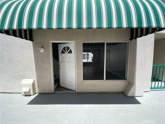 Front view of a building entrance with a striped awning and an open door.