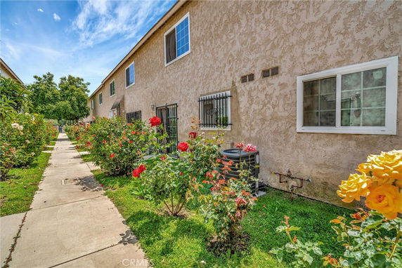 Side view of a multi-story building with a walkway and a garden of colorful flowers.