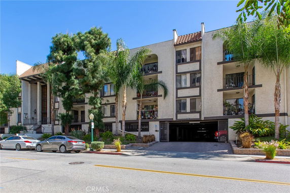 Front view of a multi-story residential building with balconies and covered parking area.