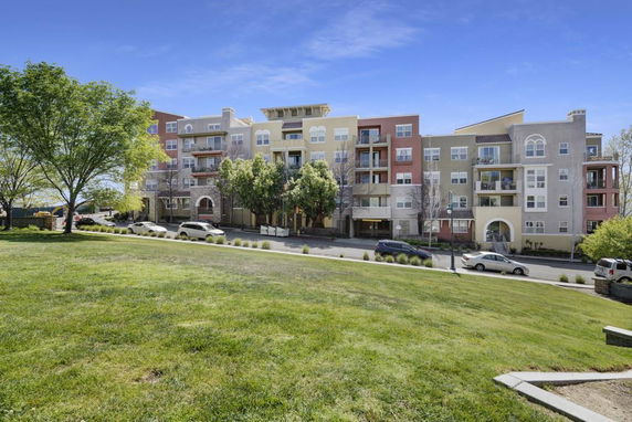 Front view of a multi-story apartment building with balconies and a variety of window designs.