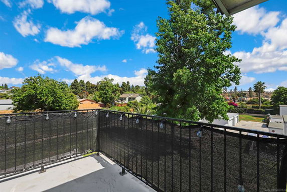 Balcony view overlooking a residential area with trees and houses in the distance.