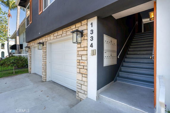 Front view of a building with two garage doors and a staircase entry.