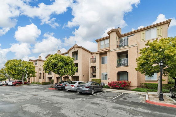 Front view of a multi-story apartment building with balconies and parking area.