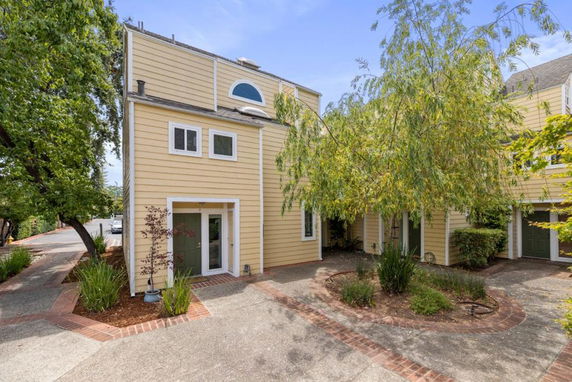 Front view of a two-story house with yellow siding and multiple windows.