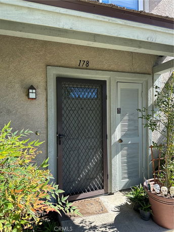 Front view of a house entrance with a mesh metal door and a small porch area.