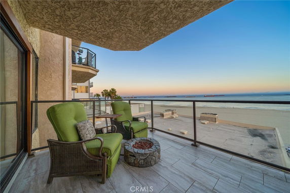Balcony overlooking the ocean with green cushioned chairs and a small table.