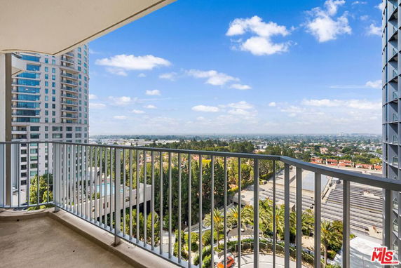 View from a balcony overlooking a cityscape with distant buildings.