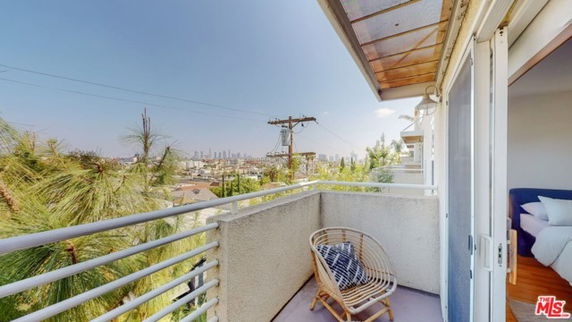 Balcony with a chair overlooking a cityscape view.
