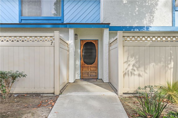 Front view of an entrance to a building with a wooden door and white fence.