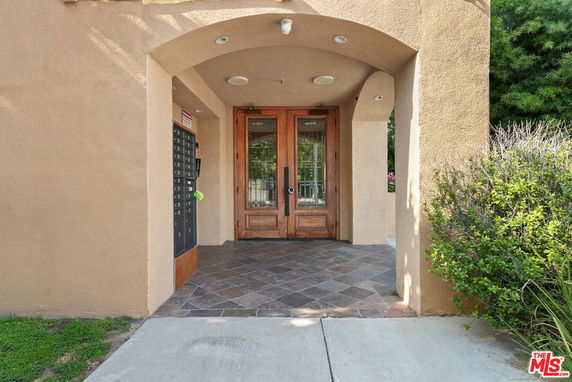 Entrance view of a building with wooden double doors and mailbox area.