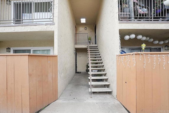 Front view of a multi-level apartment building with external stairs and balcony.