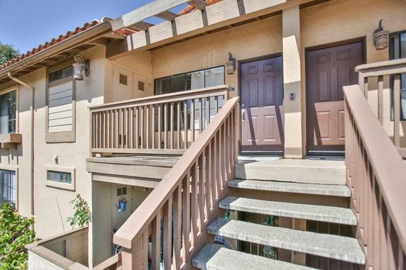 Front view of a two-story building with external stairs leading to the entrance.