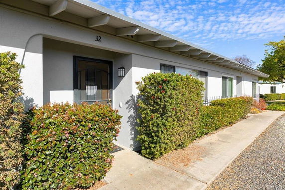 Front view of a single-story building with shrubs along the pathway.