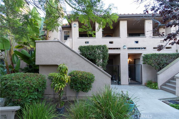 Front view of a multi-story building with exterior stairs and gated entrances.