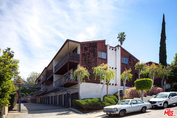 Front view of a multi-story residential building with a wooden exterior and balconies.