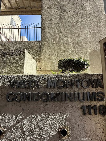 Concrete facade of a building with a sign 'VISTA MONTOYA CONDOMINIUMS 1118' and metal railing above.