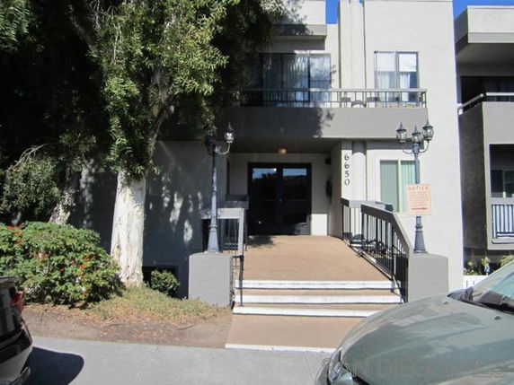 Front view of a multi-story building with a stairway entrance and columns.