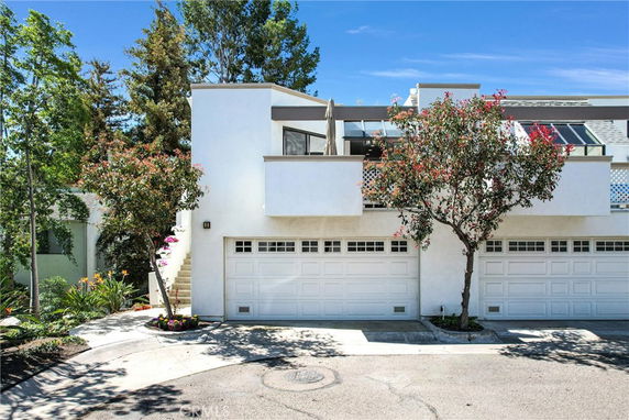 Front view of a two-story residential building with double garages and a balcony.