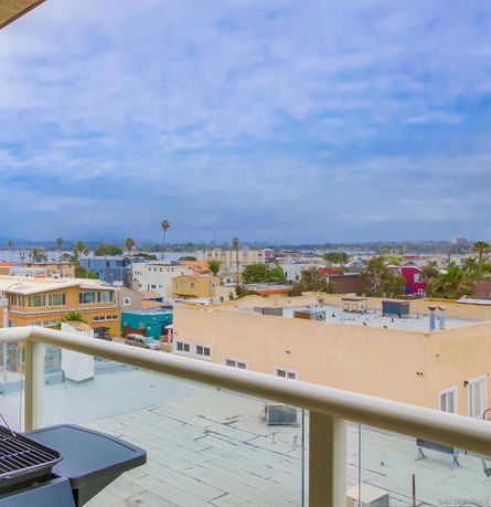Panoramic view of buildings from a higher vantage point with distant views and a grill on a balcony.