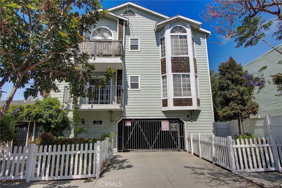 Front view of a multi-story house with balconies and a gated driveway.