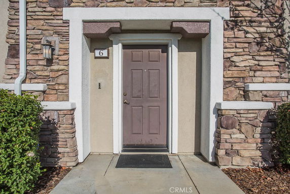Front view of a house entrance with stone facade and a brown door.
