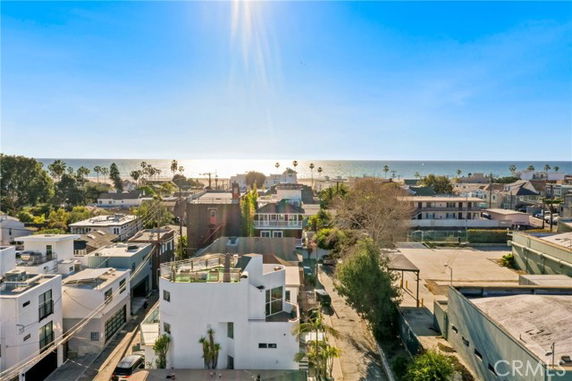 Wide-angle view of buildings and ocean with the sun shining in the background.