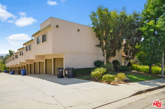 Front view of a row of multi-story townhouses with garages on the ground floor.