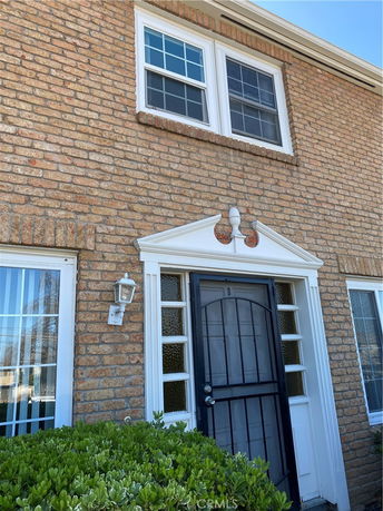 Front view of a two-story brick house with a black front door and white-framed windows.