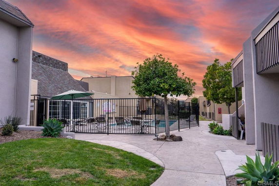 Outdoor view of a swimming pool area surrounded by residential buildings with a sunset sky.