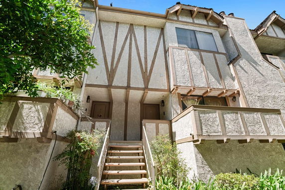 Front view of a multi-story house with a staircase leading to the entrance.