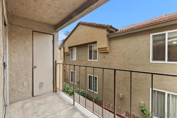 View from a balcony facing neighboring building with stucco walls and windows.