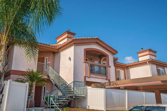 Front view of a two-story house with balconies and exterior stairs.