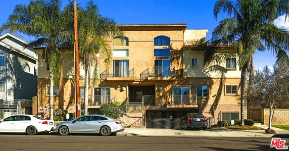 Front view of a multi-story building with balconies and an arched window design.