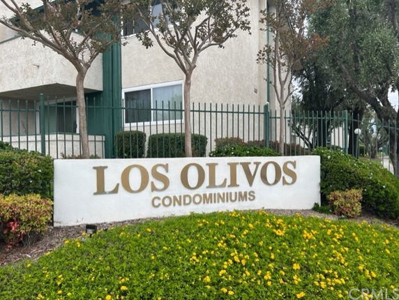 Front view of a condominium building with a sign reading 'Los Olivos Condominiums'.