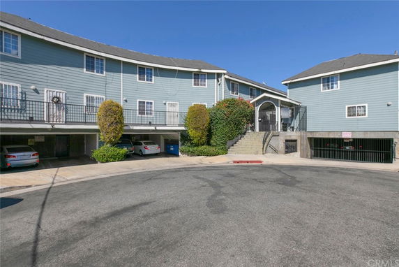 Front view of a multi-story residential building with parking area underneath and external stairway.