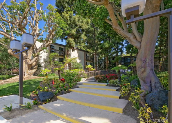 Front view of a residential building surrounded by trees and landscaped gardens.