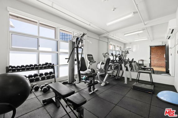 Indoor gym with exercise equipment including treadmills, weight racks, and exercise bikes.