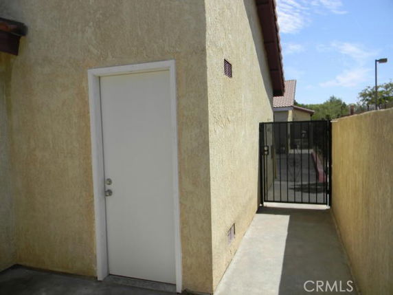 Side view of a building with a narrow walkway and a white door.