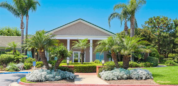 Front view of a building with columns and a gable roof surrounded by palm trees.