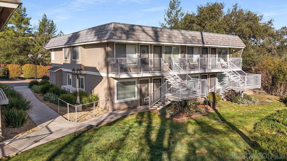 Front view of a two-story residential building with exterior staircases and a sloped roof.