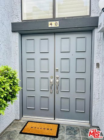 Front view of a building entrance with a double door and a welcome mat.