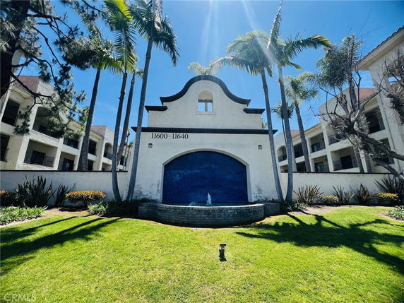 Front view of a multi-story building with a decorative facade and palm trees.
