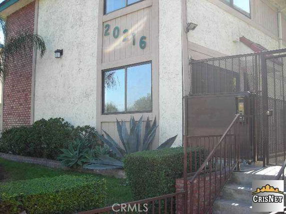 Front view of a building with a plant and stairs leading to the entrance.