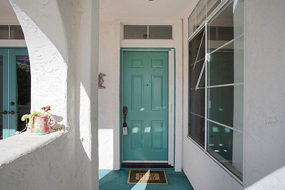 Front view of a house entrance with a turquoise door and adjacent windows.
