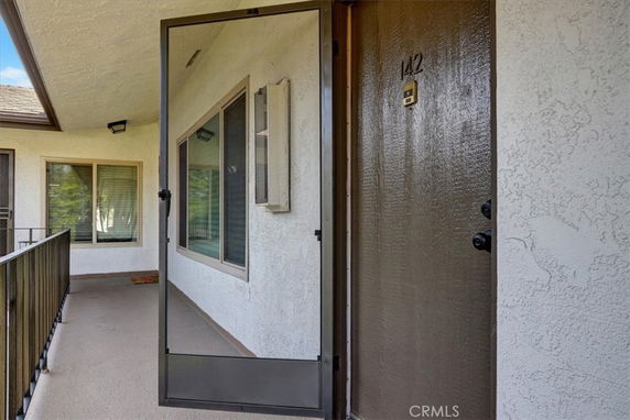 Entryway view of a residential building with a balcony and a screen door.